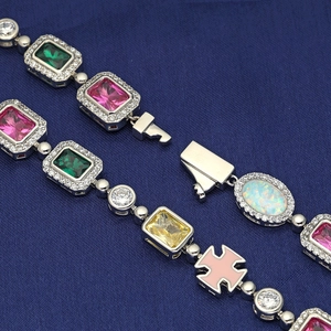 Dettaglio di un bracciale con pietre colorate, tagli misti e ciondolo a croce in smalto rosa