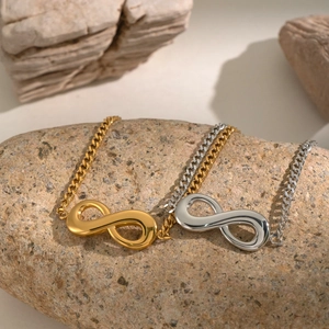 Detail of gold and silver infinity bracelets on natural stone, high-polish finish