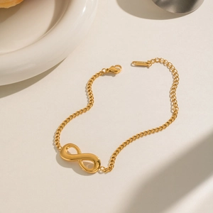Macro view of gold-plated infinity symbol bracelet with lobster clasp and adjustable chain