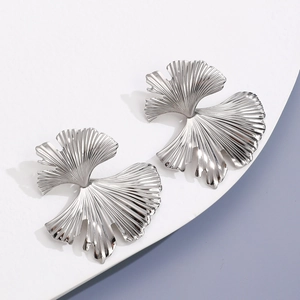Close-up of silver ginkgo leaf earrings with radial pleated texture and metallic finish
