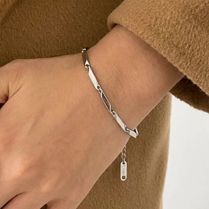 Detailed close-up of a silver stainless steel geometric link bracelet on a woman's wrist