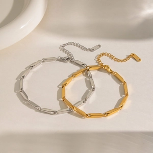 Detailed shot of interlocking gold and silver geometric link bracelets on white pedestal