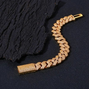 Close-up of 15mm gold Cuban link bracelet with iced-out zircon pave on a dark textured base
