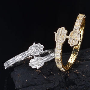 Macro shot of gold and silver Hamsa hand bracelets with cubic zirconia on black stone