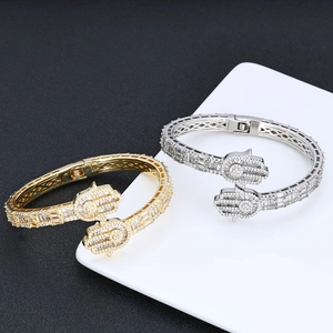 Detail of gold and silver Hamsa Hand bracelets with pavé zircons and hollow geometric side