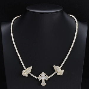 Detail of hip hop gold necklace with praying hands and iced out cross on a black mannequin