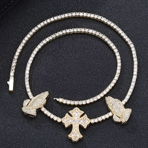 Macro shot of gold hip-hop tennis chain with iced-out cross and praying hands pendants