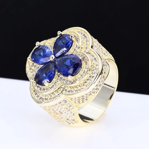 Macro side view of gold four-leaf clover ring with blue pear-cut stones and white pavé gems