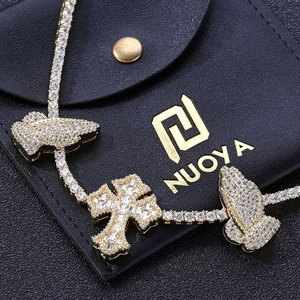 Macro detail of gold-plated hip hop necklace with prayer hands and cross pendant with zircons
