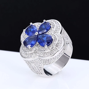 Macro shot of silver ring with four-leaf blue gemstone petals and micro-pave diamond accents
