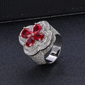 Detailed top view of a flower ring with four pear-cut red stones and micro-pave zircons