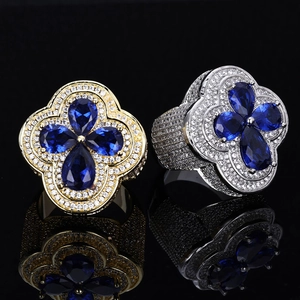 Detail of luxury hip hop rings in gold and silver with blue clover-shaped stones