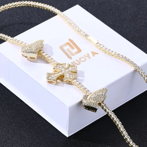 Close-up of golden tennis chain with iced-out cross and butterfly pendants in a gift box