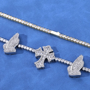 Macro shot of gold tennis chain with iced-out silver cross and praying hands pendant