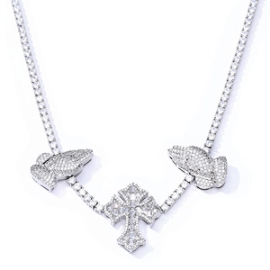 Macro detail of silver S925 tennis chain with moissanite cross and praying hands pendant