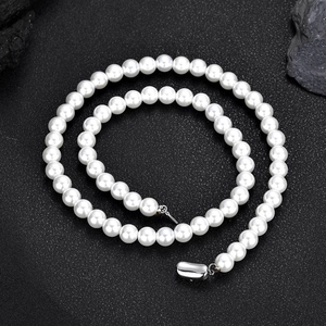 Élégant collier de perles blanches 8mm avec fermoir en argent sur fond texturé noir