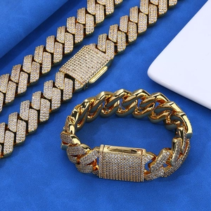 Vista macro de conjunto de cadena cubana dorada con circonitas sobre terciopelo azul