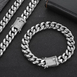Close-up of silver Cuban link chain set with a diamond-encrusted clasp on black background