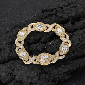 Hip hop style gold Cuban link bracelet with eye-shaped zircon accents on black rock