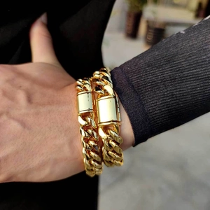 Gros plan de bracelets gourmettes dorés épais avec fermoirs rectangulaires pour hommes