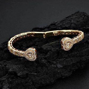 Detailed view of a gold-plated heart bracelet with zircon pavé on a textured stone base