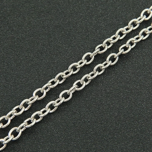 Macro shot of silver O-chain necklace links and polished metal texture on black surface