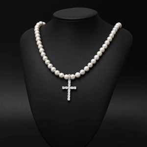 Détail d'un collier de perles 8mm avec un pendentif croix serti de strass brillants