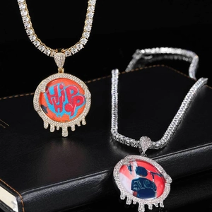 Détail de pendentifs hip hop porte-photo sertis de zircons sur fond noir texturé