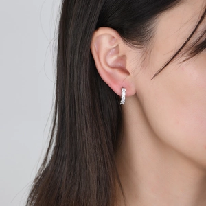 Close-up of a silver-toned earring featuring five inlaid zircons on a model ear
