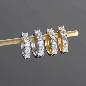 Close-up of gold and silver hip hop earrings with five rows of zircon on a display stand