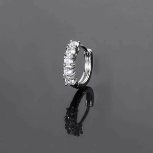 Macro shot of a silver hoop earring featuring five sparkling white zircons on a reflective surface
