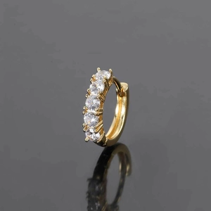 Detailed macro view of gold hoop earrings with five round-cut cubic zirconia stones