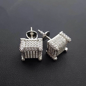 Macro shot of silver square iced out stud earrings with screw back on dark leather