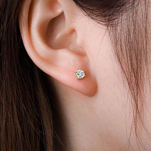 Classic round brilliant cut zircon stud earrings with gold four-prong setting on ear lobe