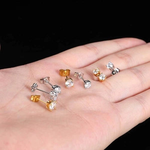 Detail of round cubic zirconia stud earrings in gold and silver held in palm