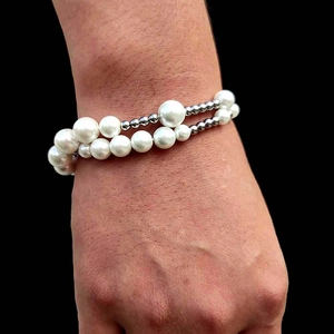 Detail of a double-layered pearl and metallic bead bracelet worn on a female wrist
