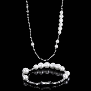 Detail showing pearl and stainless steel bead necklace with a bow pendant on black background