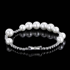 Elegant pearl and silver bead bracelet with a stylish metal bow pendant on black mirror