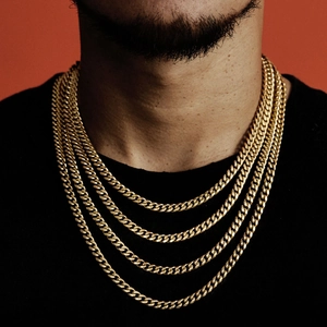 Detailed view of layered gold Cuban link chains on a male model with orange background