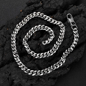 Polished silver stainless steel Cuban link necklace for men on black stone background