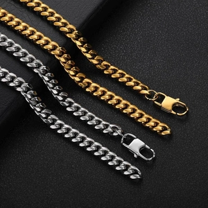 Gold and silver stainless steel Cuban link chains with lobster clasps on leather backdrop