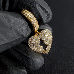 Macro-detail van iced-out gebroken hart hanger in goud met micro-pave kristallen