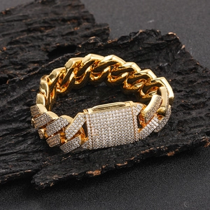 Detalle de cadena cubana dorada con circonitas brillantes sobre fondo de madera
