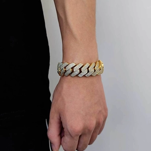 Detail van gouden cubaanse armband met zirkonen om de pols van een man in hiphopstijl