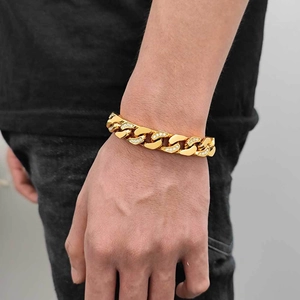 Detailed view of gold 12mm Cuban link bracelet with CNC set zircons on a male wrist
