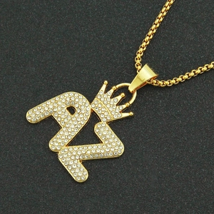 Collier doré avec pendentif chiffre 21, couronne et cristaux sur fond noir texturé