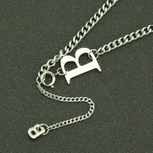 Collana minimalista argentata con pendente lettera B e catena cubana su sfondo nero