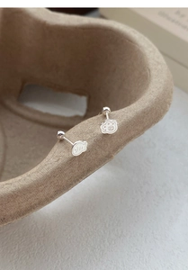 Macro shot of S999 silver cat paw and fish bone earrings with secure screw back design