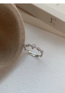 Close-up detail of silver floral branch ring with sparkling zircon stones and open band