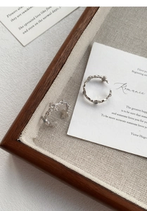 Detailed close-up of two S925 sterling silver hollow flower rings on a rustic wood tray